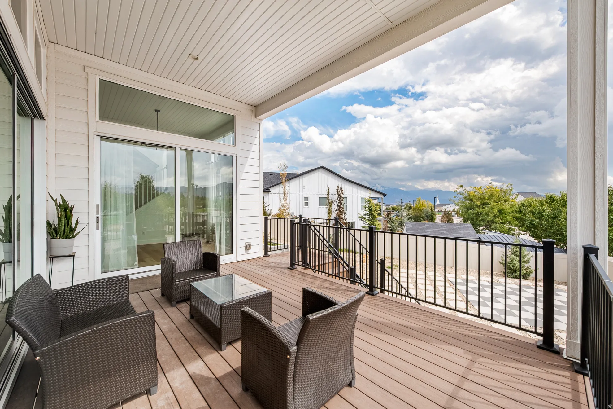 Covered outdoor deck with composite decking, white soffit ceiling, and black metal railing