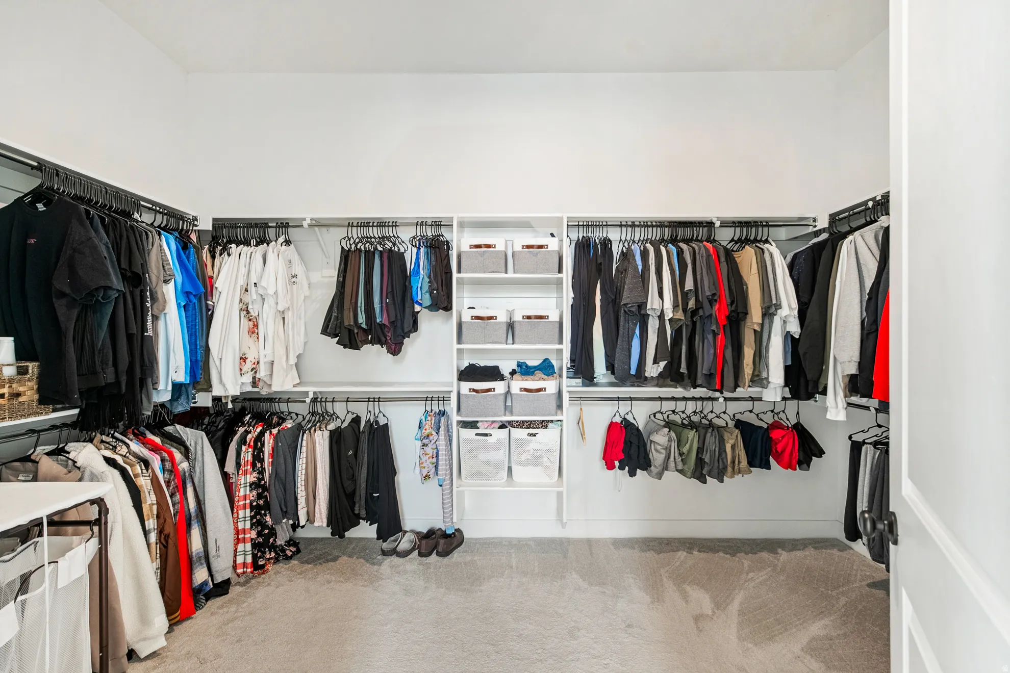 Walk-in closet featuring extensive built-in shelving, multiple hanging rods, and light-toned carpeting