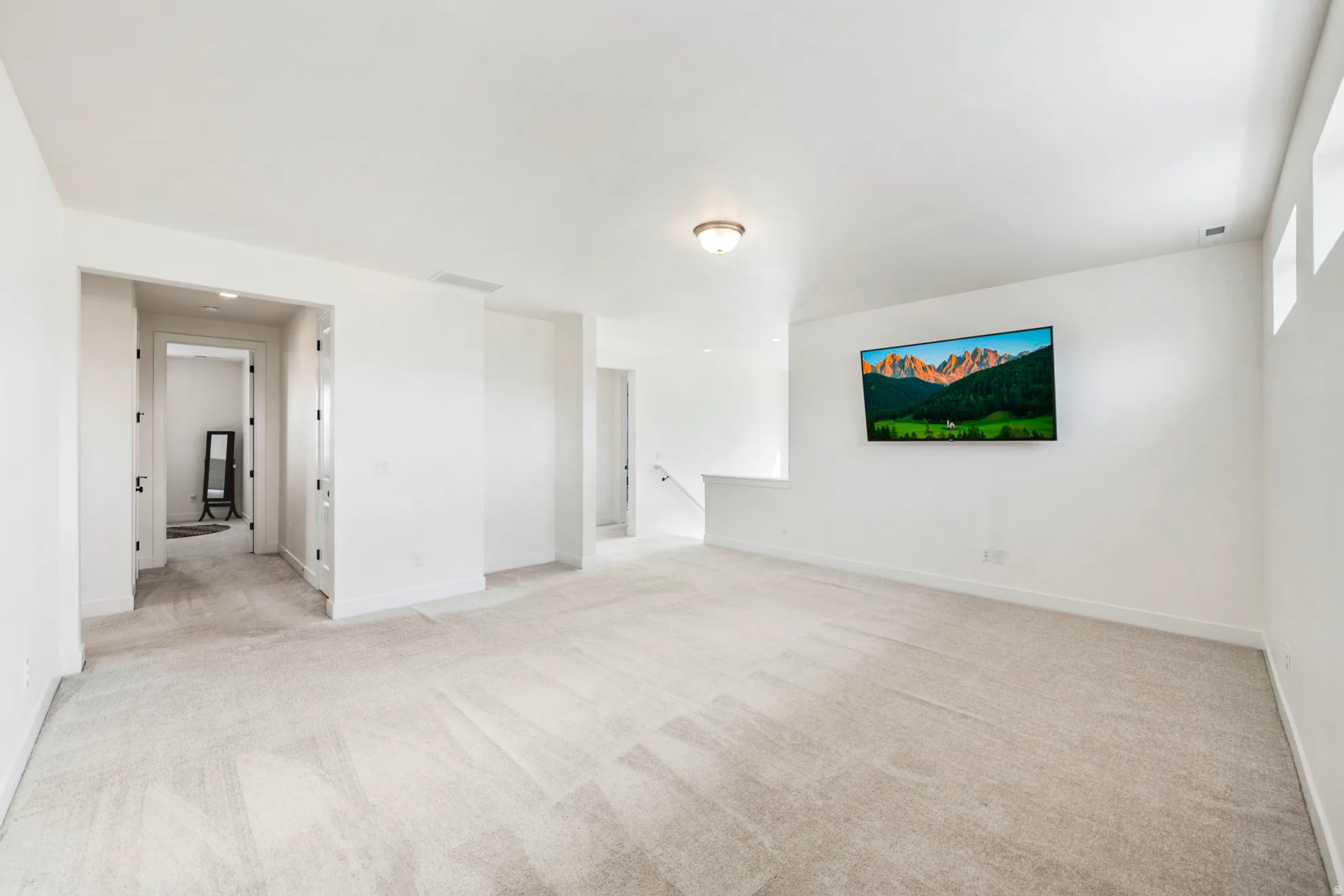 Carpeted room with white walls, recessed lighting, and a wall-mounted television