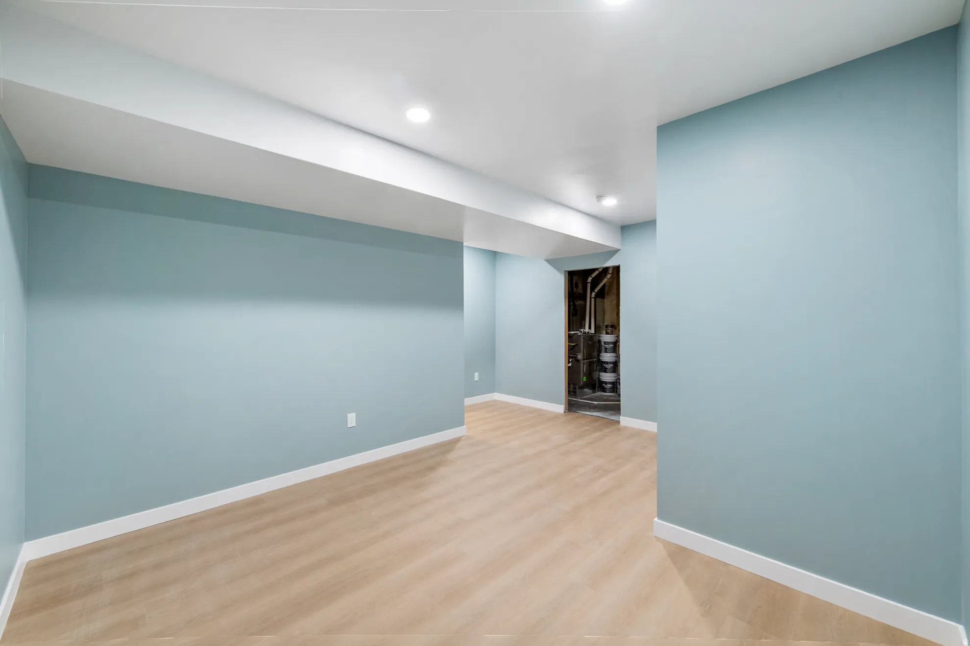 Recessed lighting, light wood-finish flooring, light blue wall paint, white trim, and a white ceiling