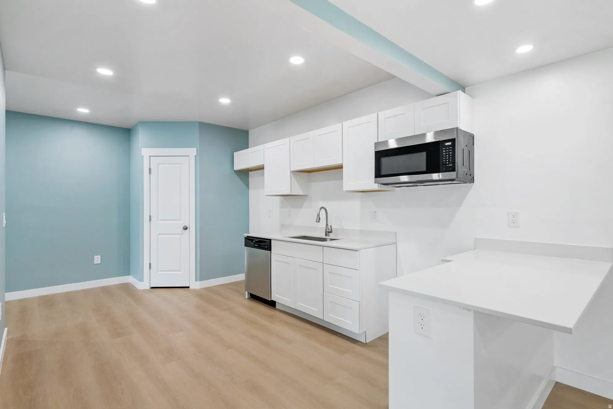 Kitchenette with white shaker cabinetry, stainless steel dishwasher, and a built-in microwave