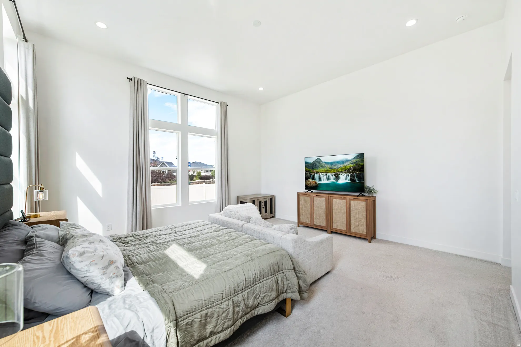 Spacious room featuring high ceilings, recessed lighting, expansive multi-pane windows, and light-toned carpeting