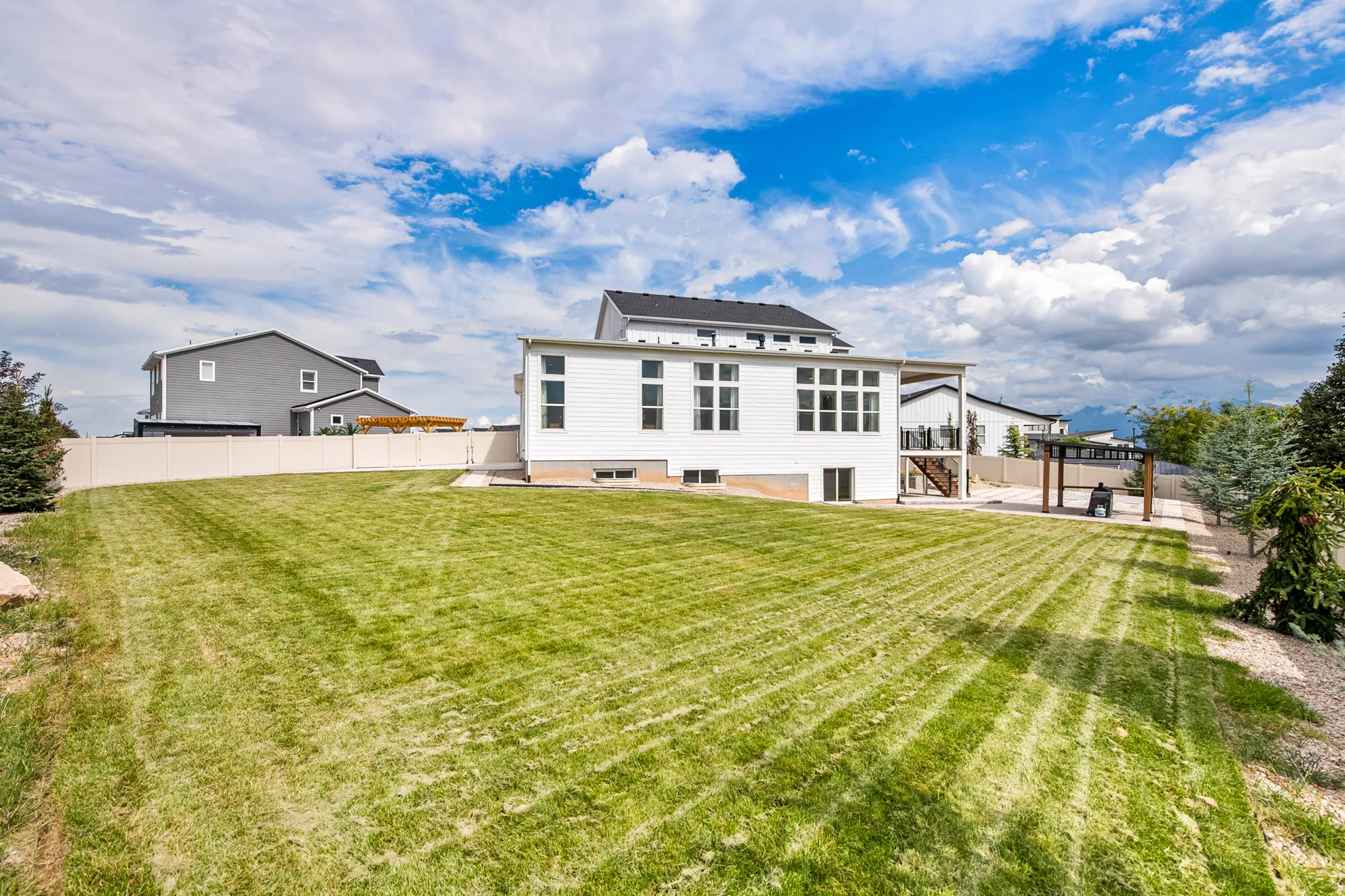 Expansive backyard with a manicured lawn, a privacy fence, and a pergola