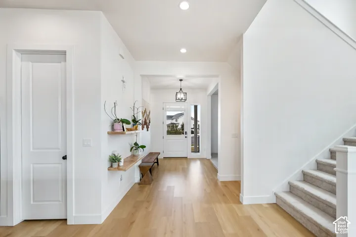 Light wood-finish flooring, recessed ceiling lighting, and a front entry door with side lites and transom