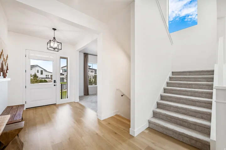 Entryway featuring wood-finish flooring, a contemporary black lantern pendant light, and a white paneled door with sidelight