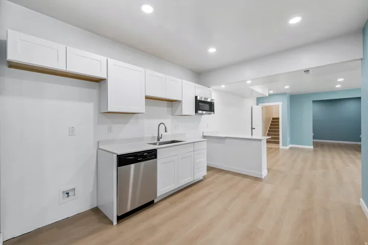 White cabinetry with matte black hardware, stainless steel dishwasher, and built-in microwave