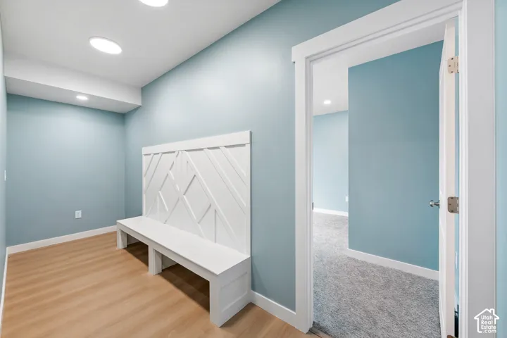 Recessed ceiling lighting, wood-finish flooring, and a built-in bench with a decorative back panel