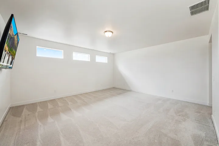 Recessed windows provide ample natural light within this expansive room, featuring neutral wall tones and a ceiling-mounted light fixture