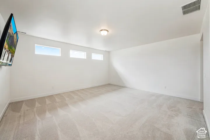 Recessed windows provide ample natural light within this expansive room, featuring neutral wall tones and a ceiling-mounted light fixture