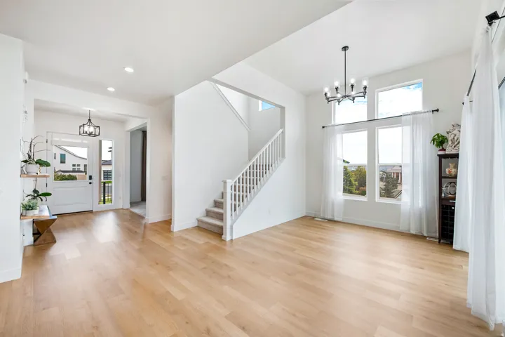 Spacious living area featuring high ceilings, large windows, wood-finish flooring, and a carpeted staircase with white railings