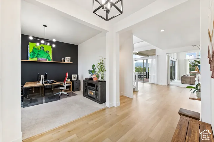 Hardwood-finish flooring, recessed lighting, and a modern chandelier illuminate this bright interior, featuring a dedicated office space with a built-in shelf