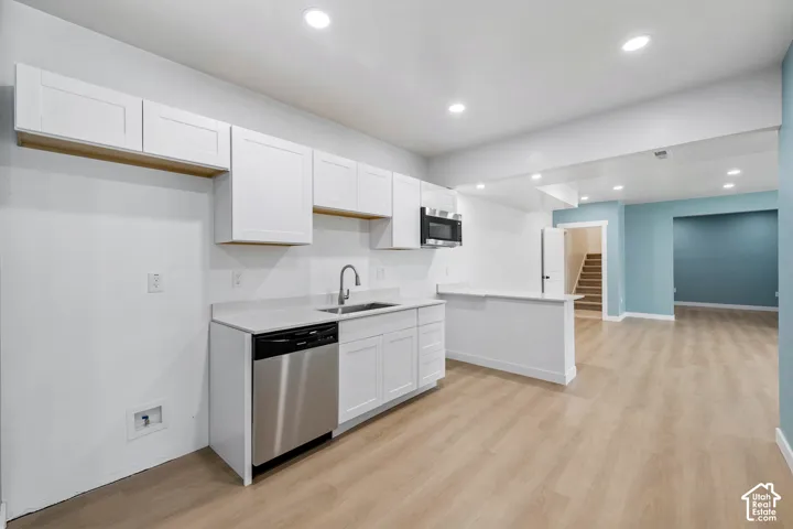 White cabinetry with matte black hardware, stainless steel dishwasher, and built-in microwave