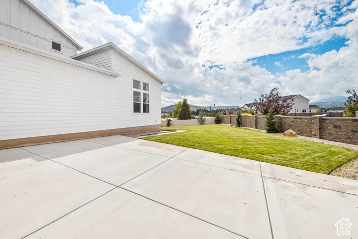 Expansive concrete patio, manicured lawn, and stone retaining wall