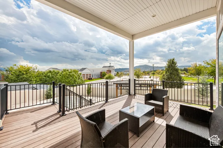 Expansive covered balcony featuring composite decking, black metal railings, and a white paneled ceiling