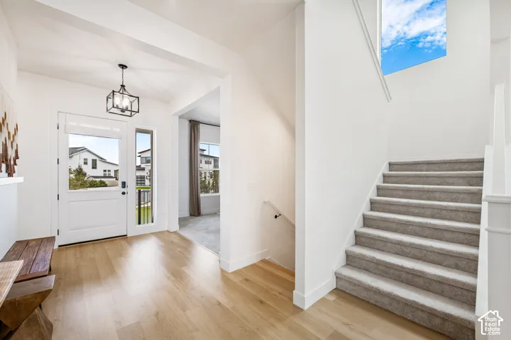 Entryway featuring wood-finish flooring, a contemporary black lantern pendant light, and a white paneled door with sidelight