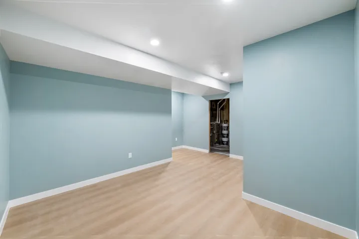 Recessed lighting, light wood-finish flooring, light blue wall paint, white trim, and a white ceiling
