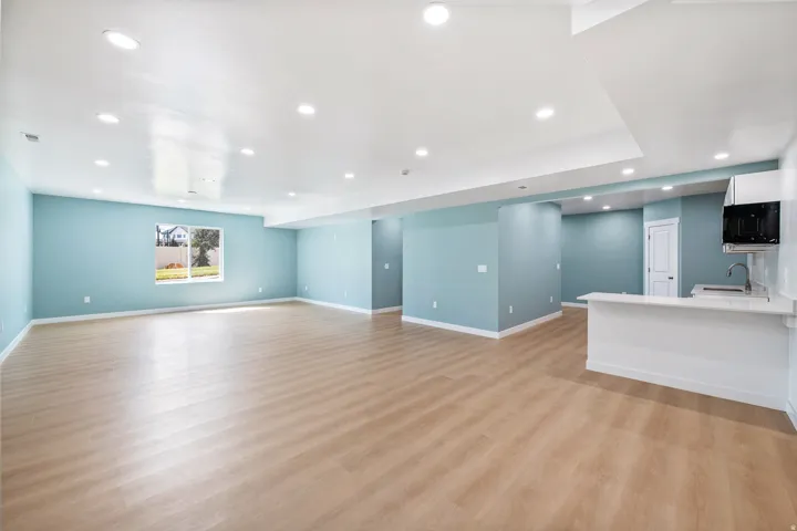Expansive open concept living area featuring wood-finish flooring, recessed lighting, and a built-in wet bar with a white countertop