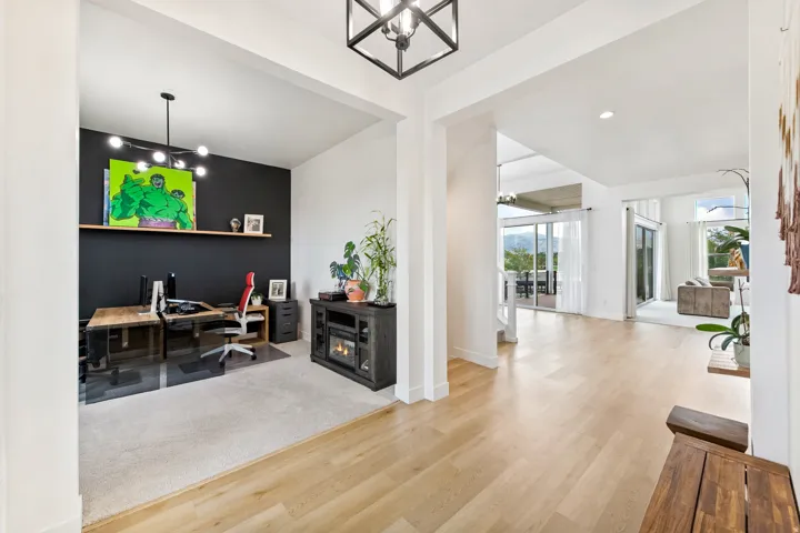 Hardwood-finish flooring, recessed lighting, and a modern chandelier illuminate this bright interior, featuring a dedicated office space with a built-in shelf