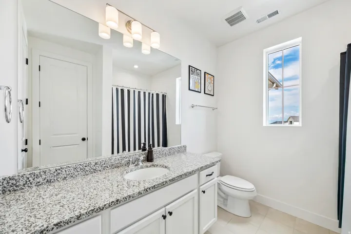 White vanity with granite-finish countertop and undermount sink