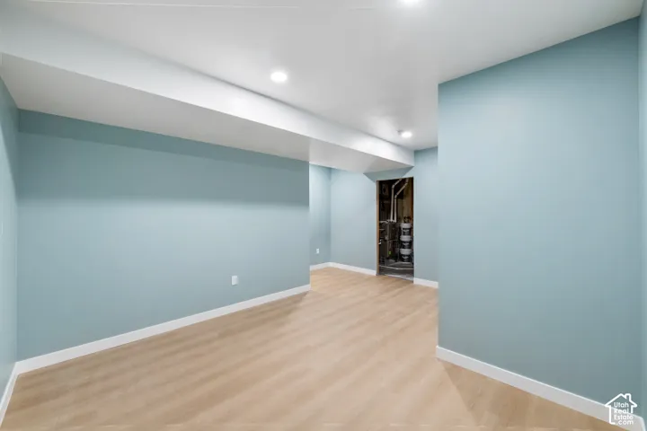 Recessed lighting, light wood-finish flooring, light blue wall paint, white trim, and a white ceiling