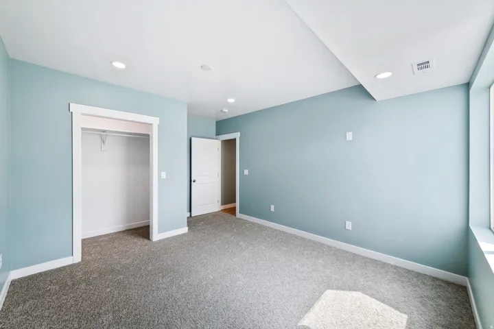 Recessed lighting, plush carpeting, light-toned walls, and an integrated closet with shelving
