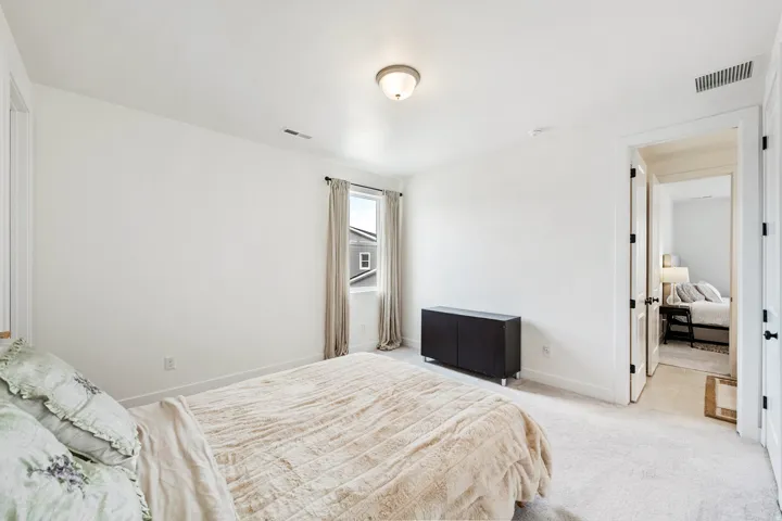 White walls with coordinating trim, neutral carpeting, and a single window with drapes