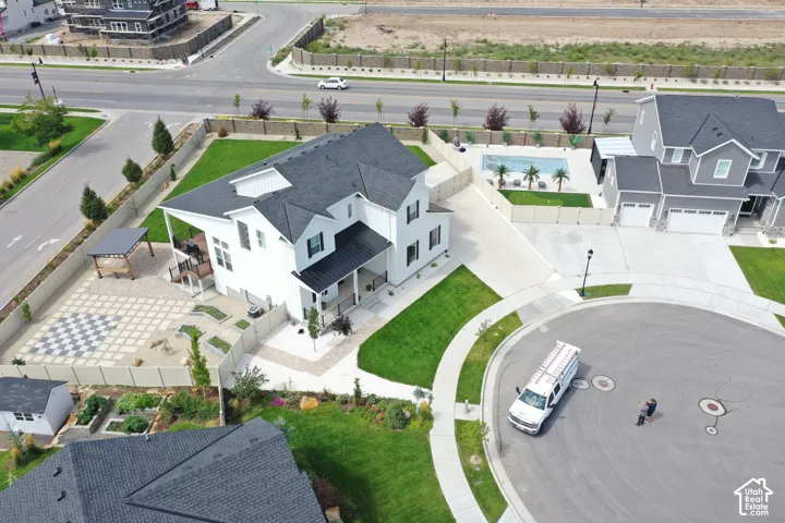 White exterior residence featuring a dark roof, covered porch, and rear patio with a checkerboard paver design