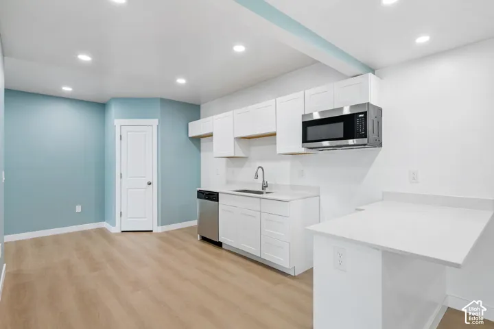 Kitchenette with white shaker cabinetry, stainless steel dishwasher, and a built-in microwave
