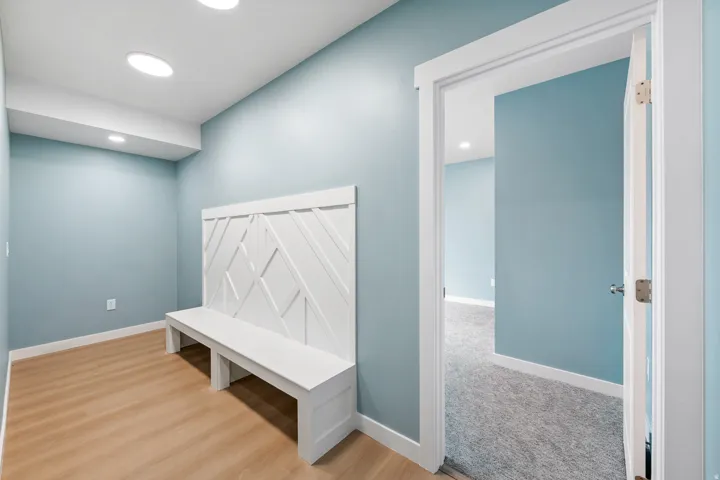Recessed ceiling lighting, wood-finish flooring, and a built-in bench with a decorative back panel