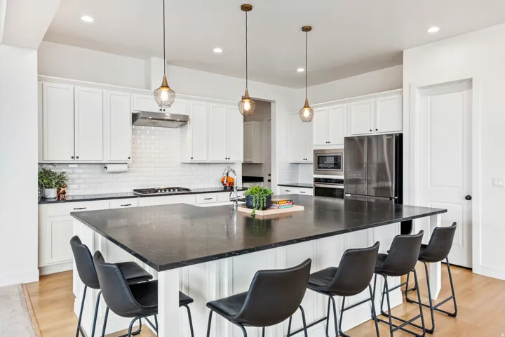 Kitchen featuring a large island with dark countertop, white shaker cabinetry, stainless steel appliances, and wood-finish flooring