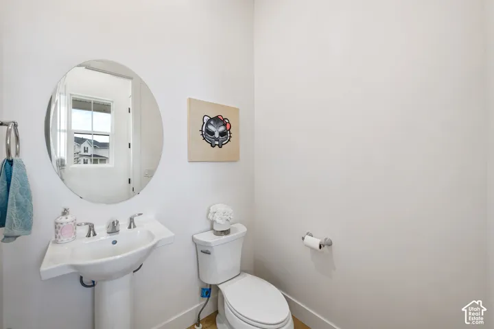 Pedestal sink with chrome fixtures, circular wall-mounted mirror, and white toilet