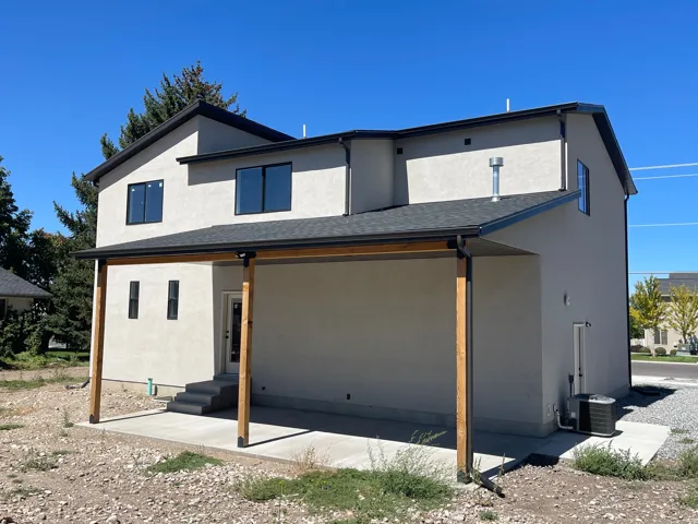Stucco exterior with black-framed windows. Covered concrete patio with wood posts.