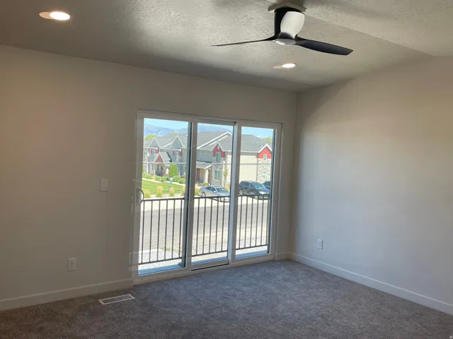 Master bedroom with sliding glass door leading to a balcony with black metal railings.