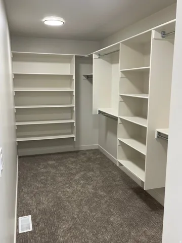 Master suite walk-in closet featuring extensive built-in shelving, multiple hanging rods, and recessed lighting.