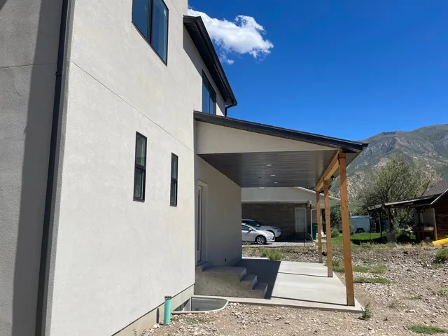 Exterior featuring stucco siding, black-framed windows, a covered patio with recessed lighting, and mountain scenery