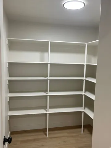Built-in shelving for organized storage, wood-finish flooring, and recessed ceiling lighting
