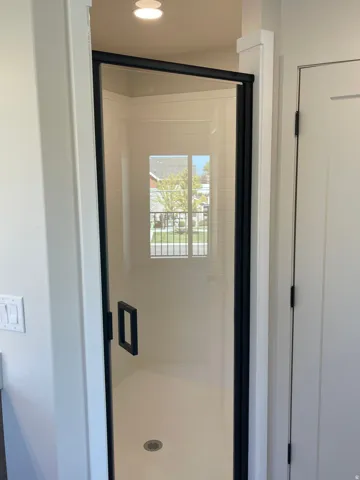 Master bathroom walk-in shower with clear glass enclosure and black framing.