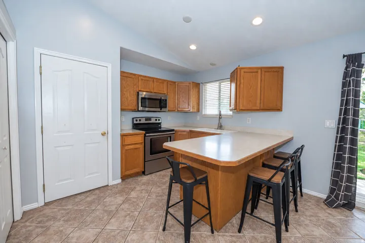 Kitchen featuring wood cabinetry, stainless steel appliances, a breakfast bar, and tiled flooring.