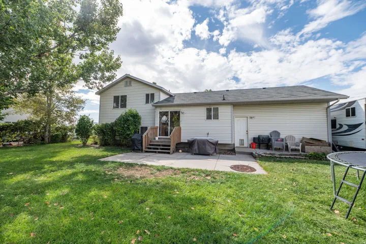 Expansive backyard with a manicured lawn, concrete patio, and a wood-finish deck