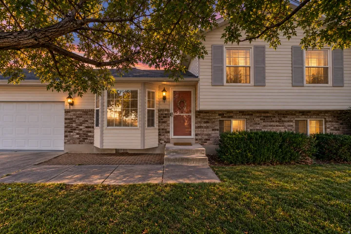 Siding exterior with brick lower facade, bay window, front entry with transom window, and an attached garage