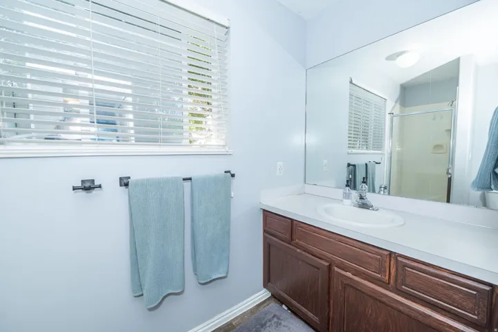 Vanity with integrated sink, wood-finish cabinetry, and expansive wall mirror