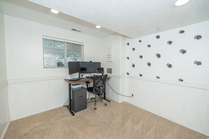 Recessed lighting illuminates this room featuring wall paneling and a textured ceiling