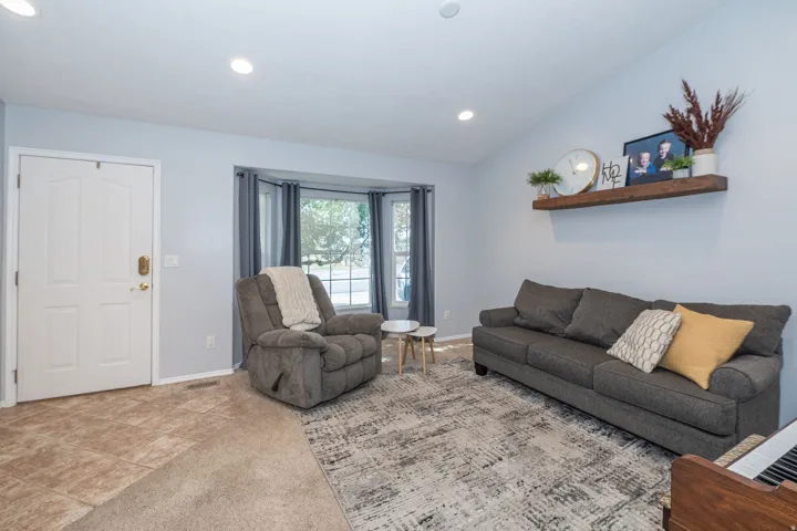 Vaulted ceiling with recessed lighting and a bay window.
