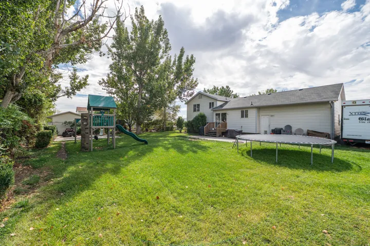 Expansive backyard with a manicured lawn, established trees, and a multi-level deck. RV Parking
