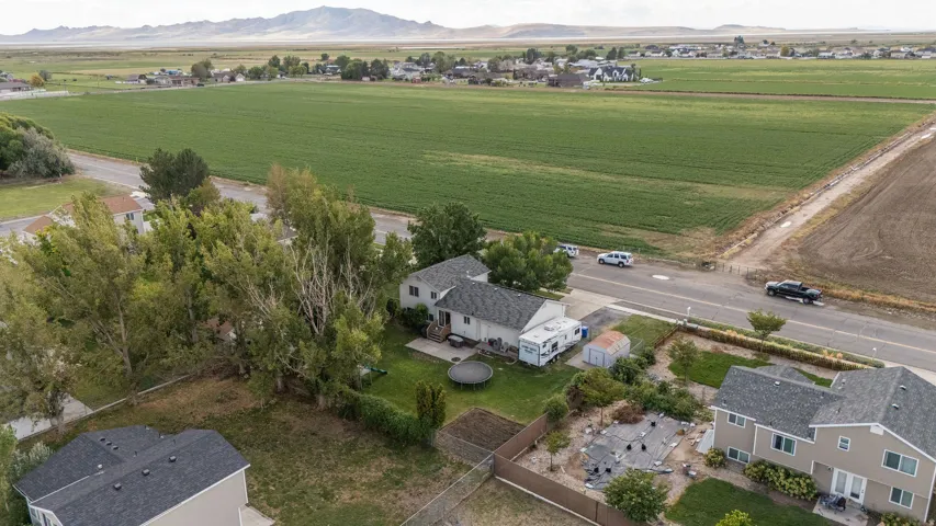 Expansive rural setting with mountain backdrop, surrounded by agricultural fields, and featuring a residential dwelling with a shingled roof