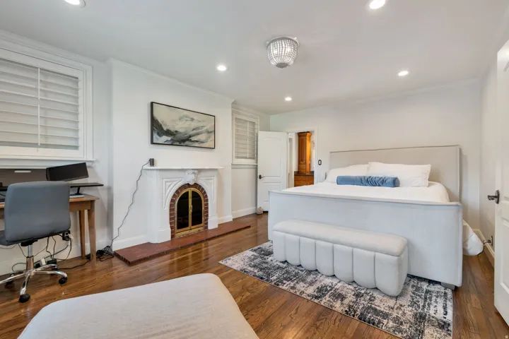 Hardwood-finish flooring with a decorative fireplace, recessed lighting, and a crystal chandelier