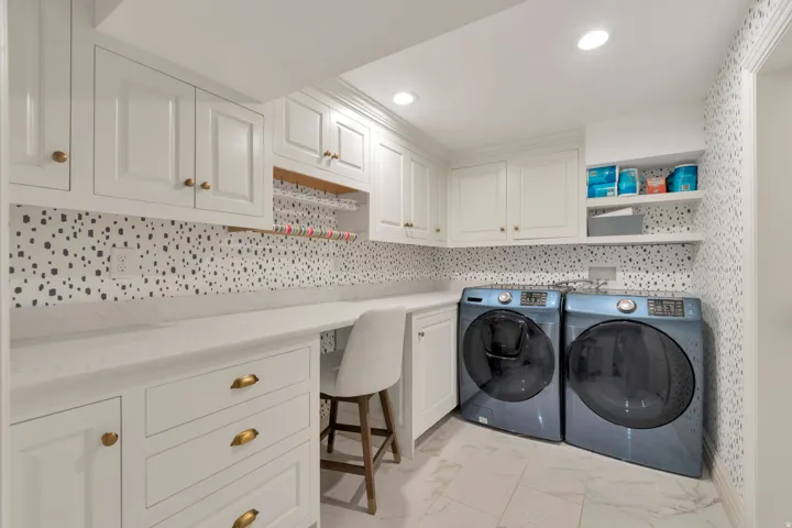 Laundry area featuring white cabinetry with brass hardware, white countertops, built-in shelving, and recessed lighting
