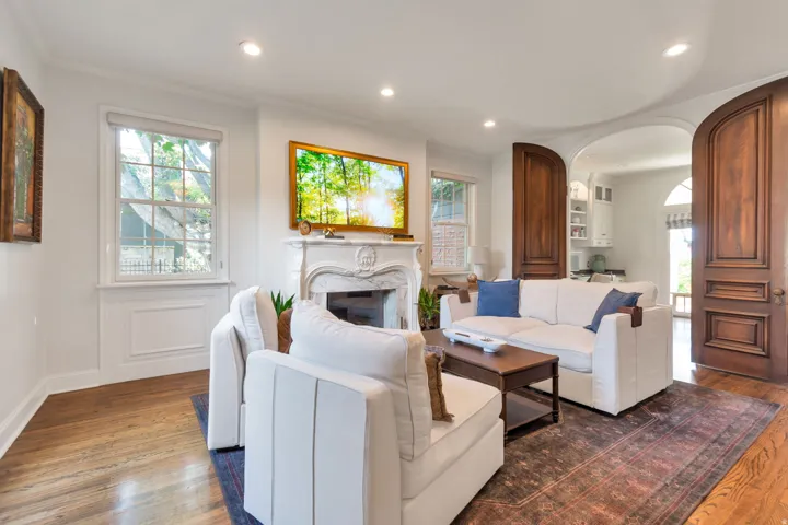 Hardwood flooring throughout, a decorative fireplace with an ornate mantel, recessed lighting, and arched doorways with wood paneling