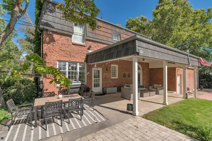 Brick exterior with a covered patio, exposed aggregate patio, and paver hardscaping