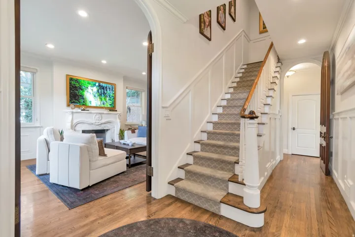 Hardwood flooring, arched doorways, wainscoting, recessed lighting, and a carved fireplace surround